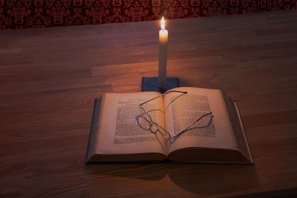 An open book beside a lit candle