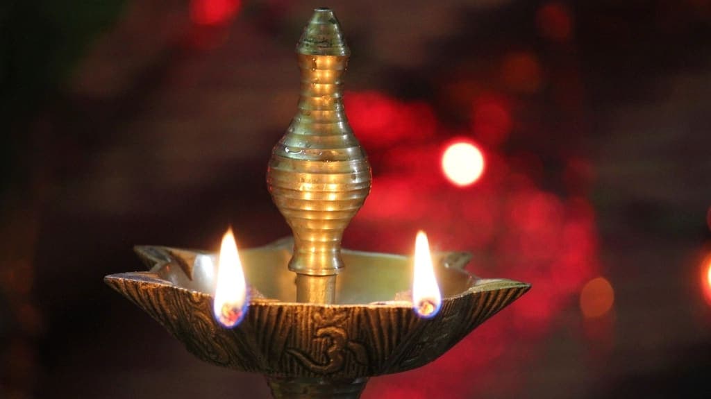 A traditional brass lamp with lit wicks