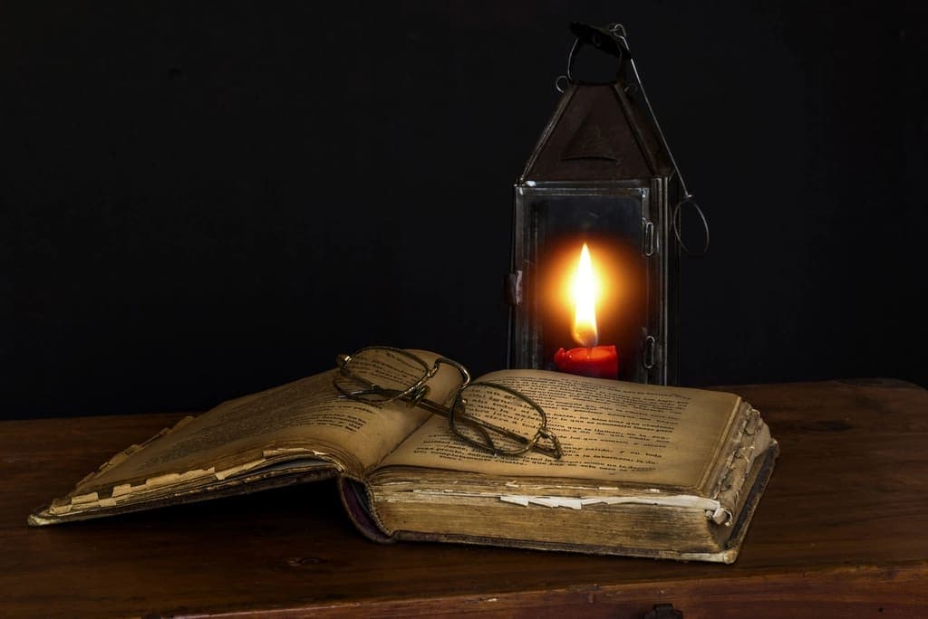 An old book beside a glowing lantern